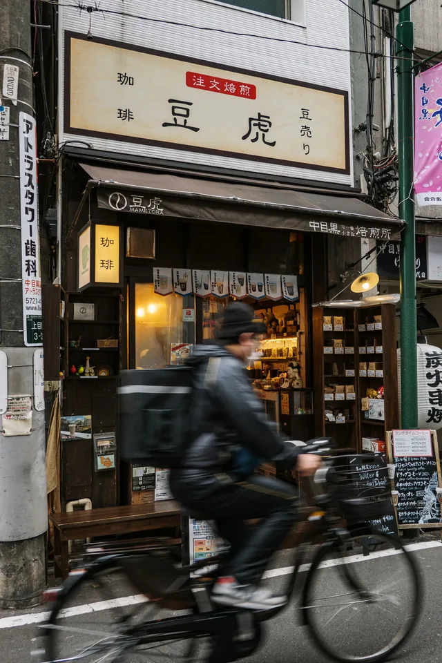 A cyclist passing a traditional Japanese coffee shop